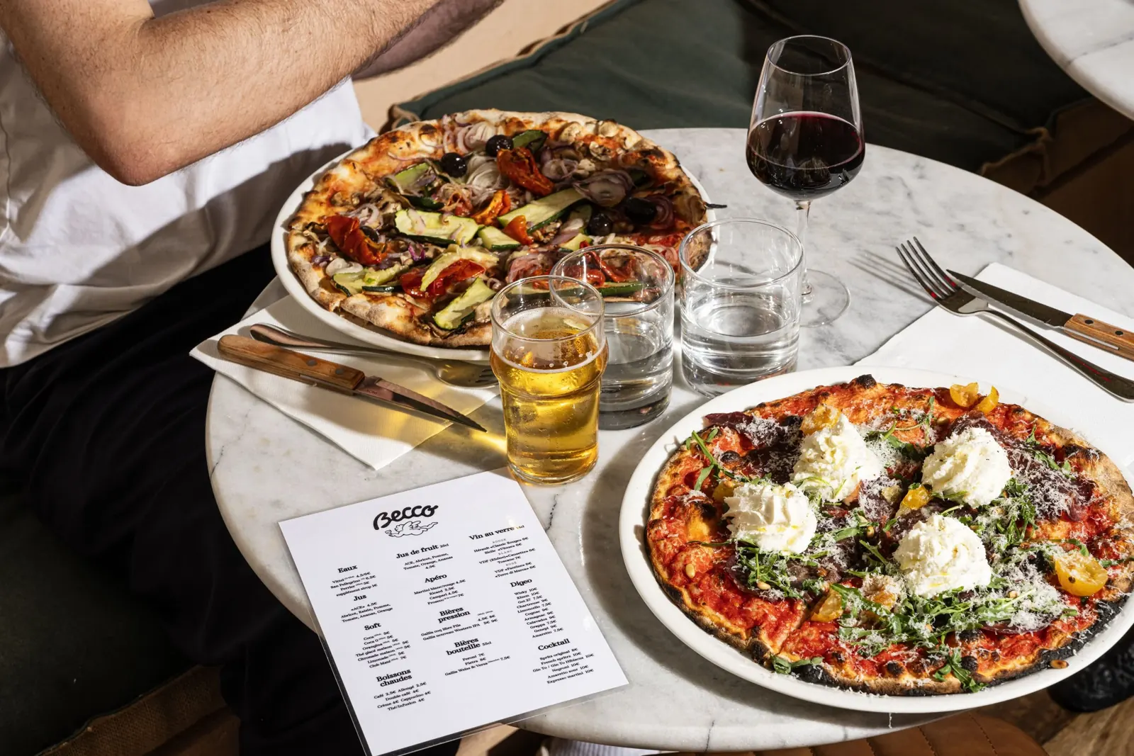 Pizzas romaines et verre de vin sur une table en marbre chez Becco